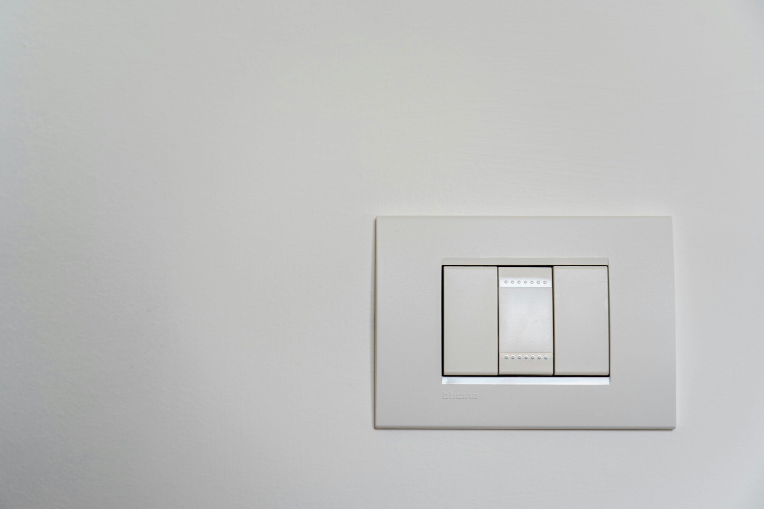 Close-up of a modern white light switch on a clean wall.